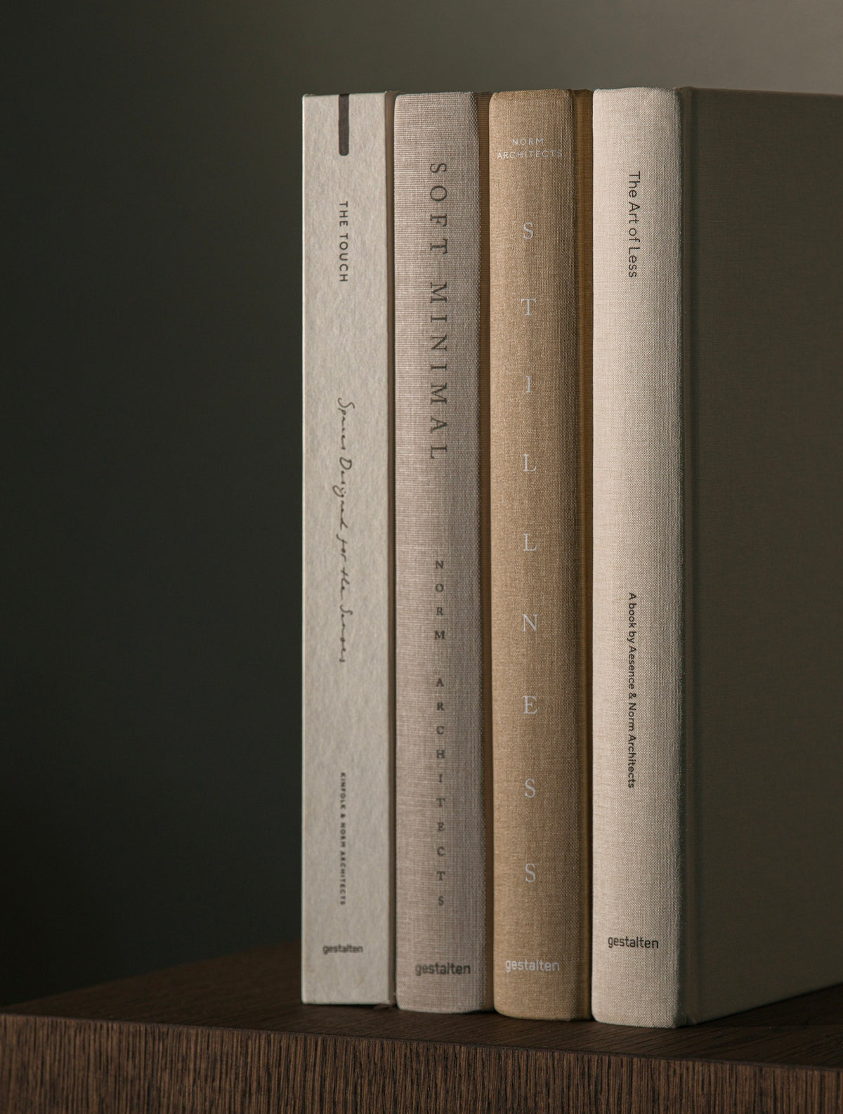 Four hardcover art books standing upright on a wooden surface against a dark background. The spines read 'The Art of Clay', 'Soft Minimal', 'Silence', and 'The Art of Clay' with visible 'postalen' branding near the bottom.