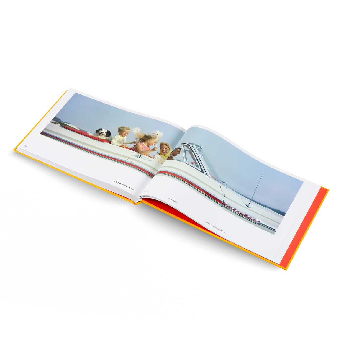 An open hardcover book showing a vintage photograph of children in a white motorboat on the water, photographed against a clean white background.