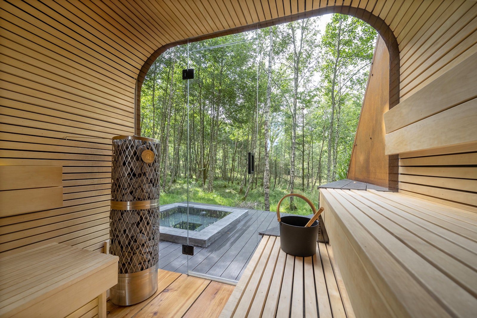 Wooden sauna with a view of a forest through a glass wall