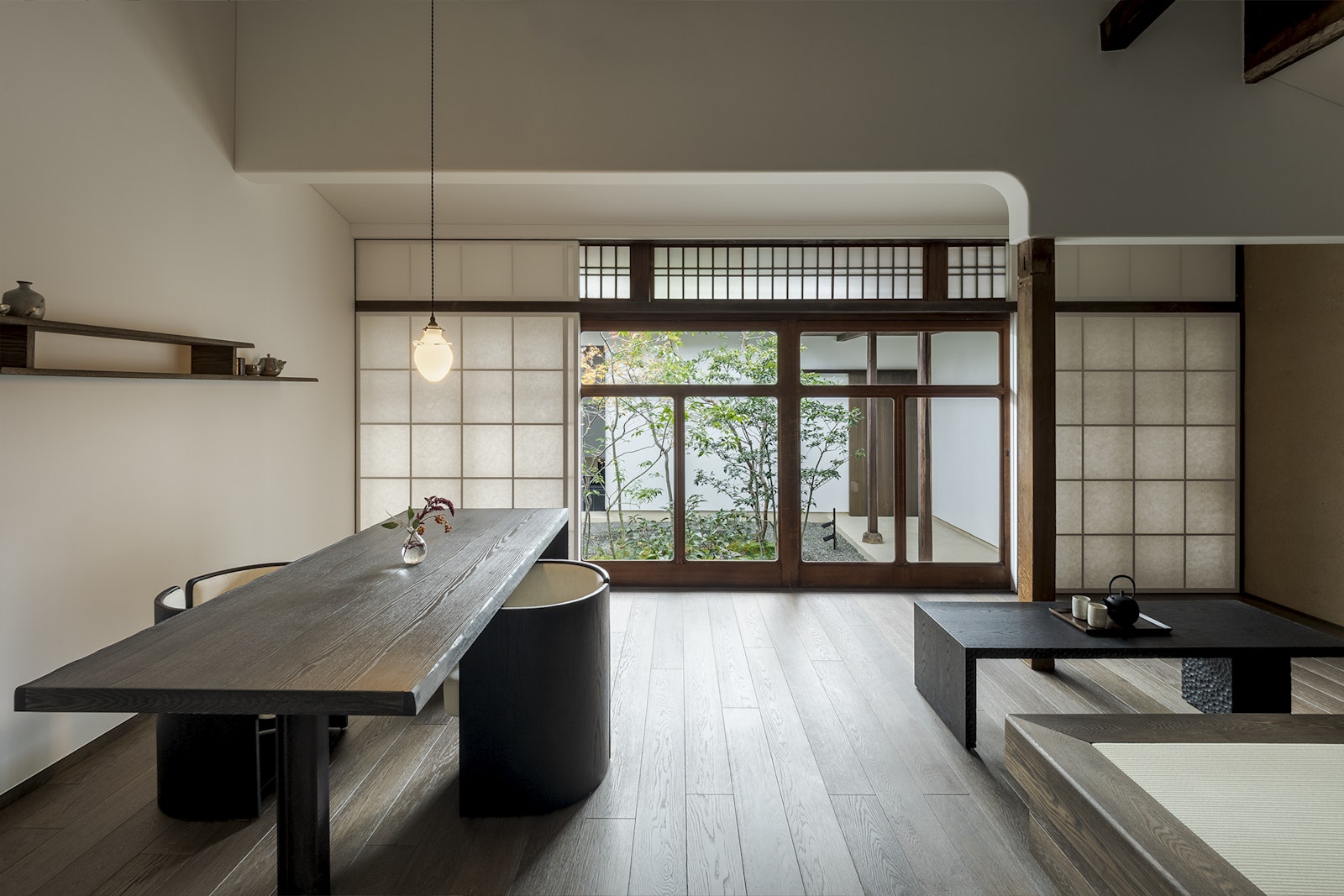 Modern interior with a long wooden table and sliding glass doors leading to an outdoor area.