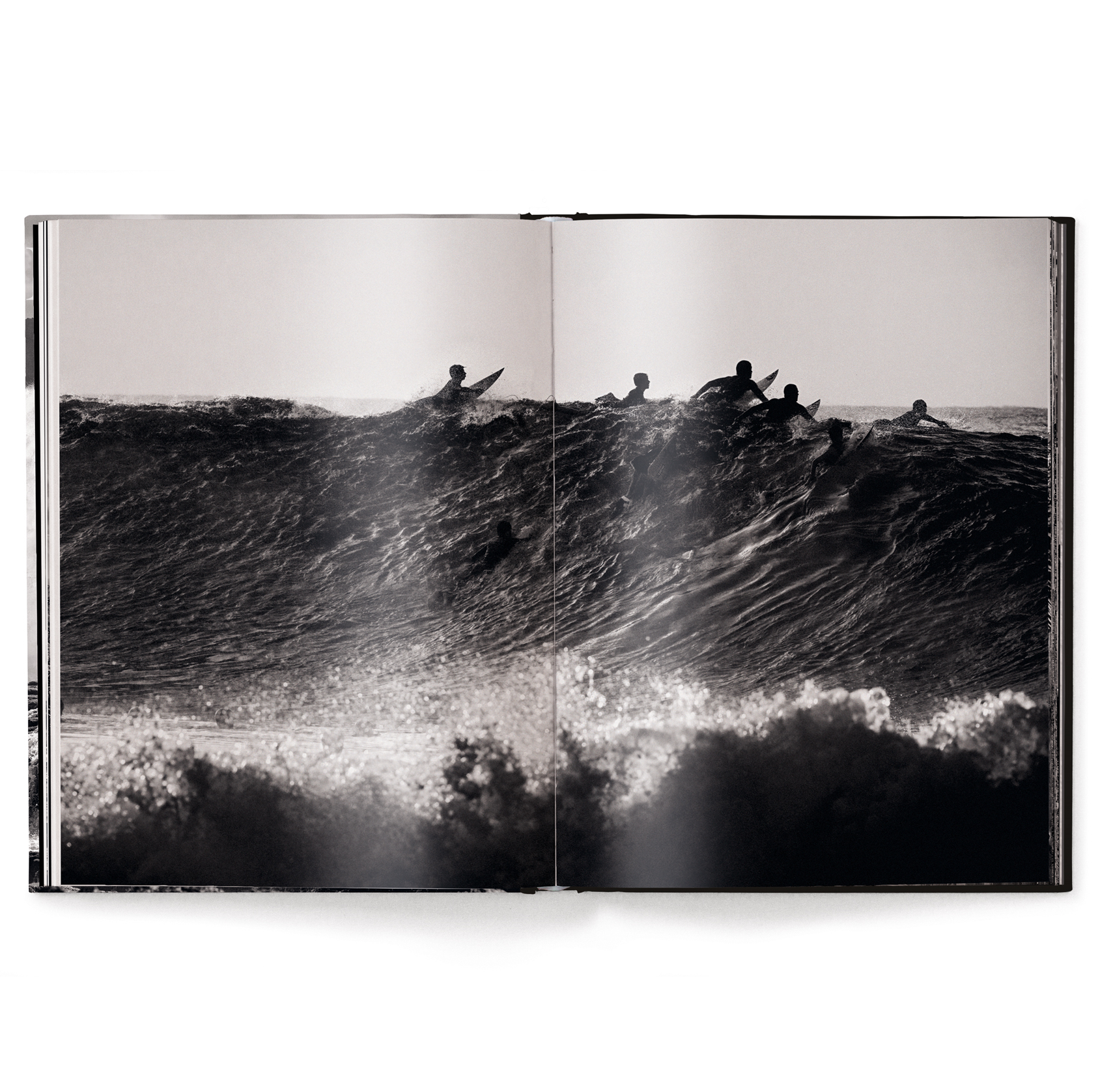 Open book showing a black and white photograph of surfers on a wave.