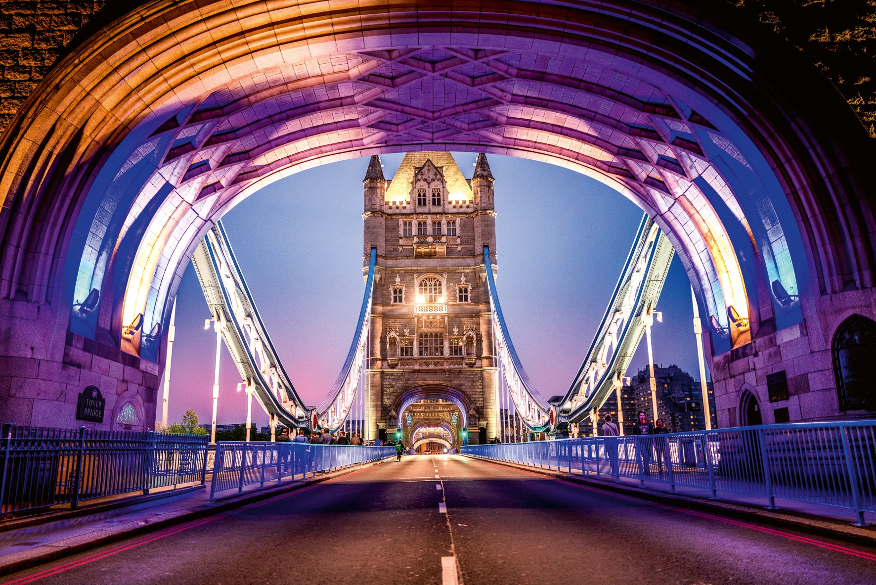 Tower Bridge in London at night with colorful arches.