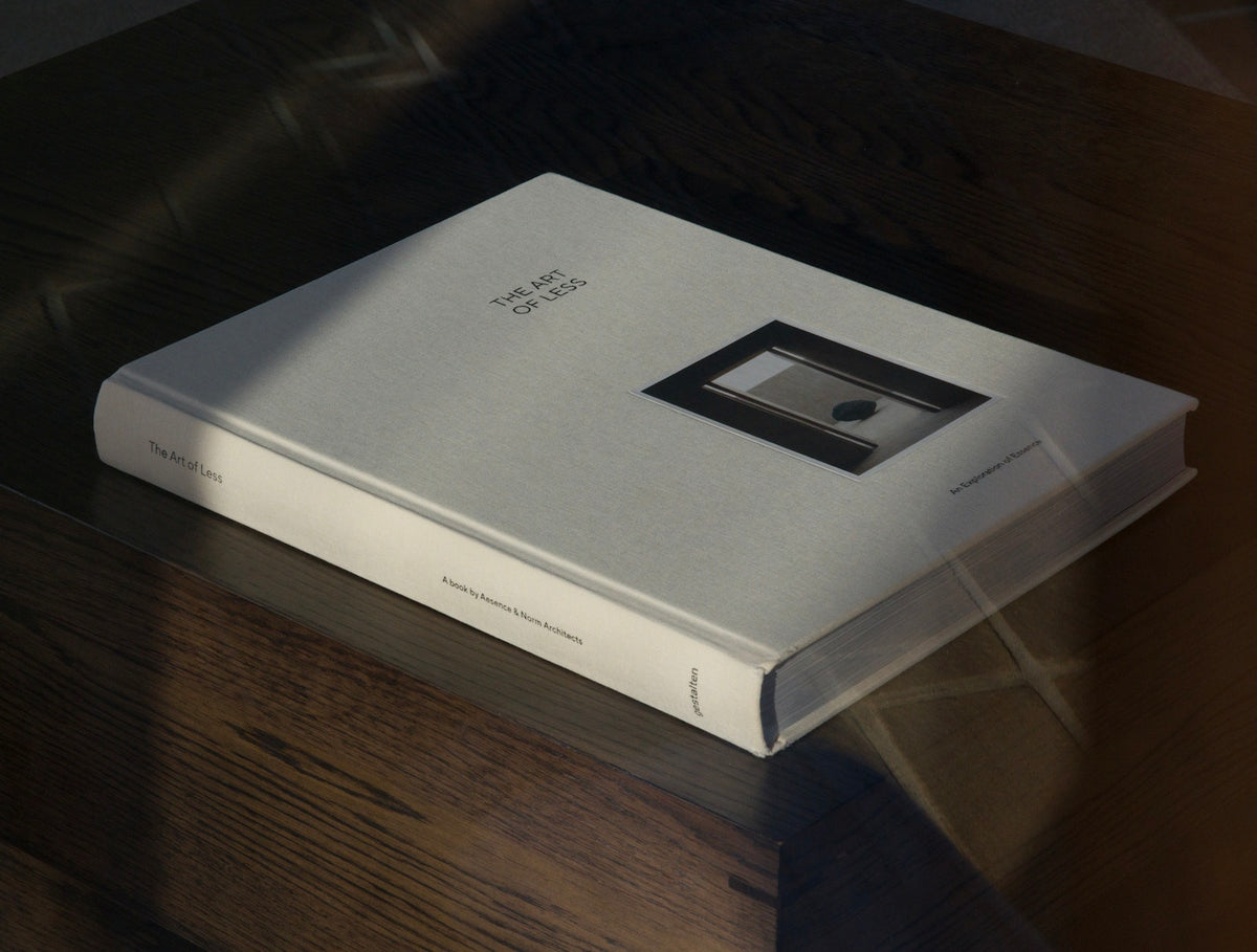 A white hardcover art book titled 'The Art of Ken' resting on a dark wooden table, featuring a minimalist black square graphic on the cover.