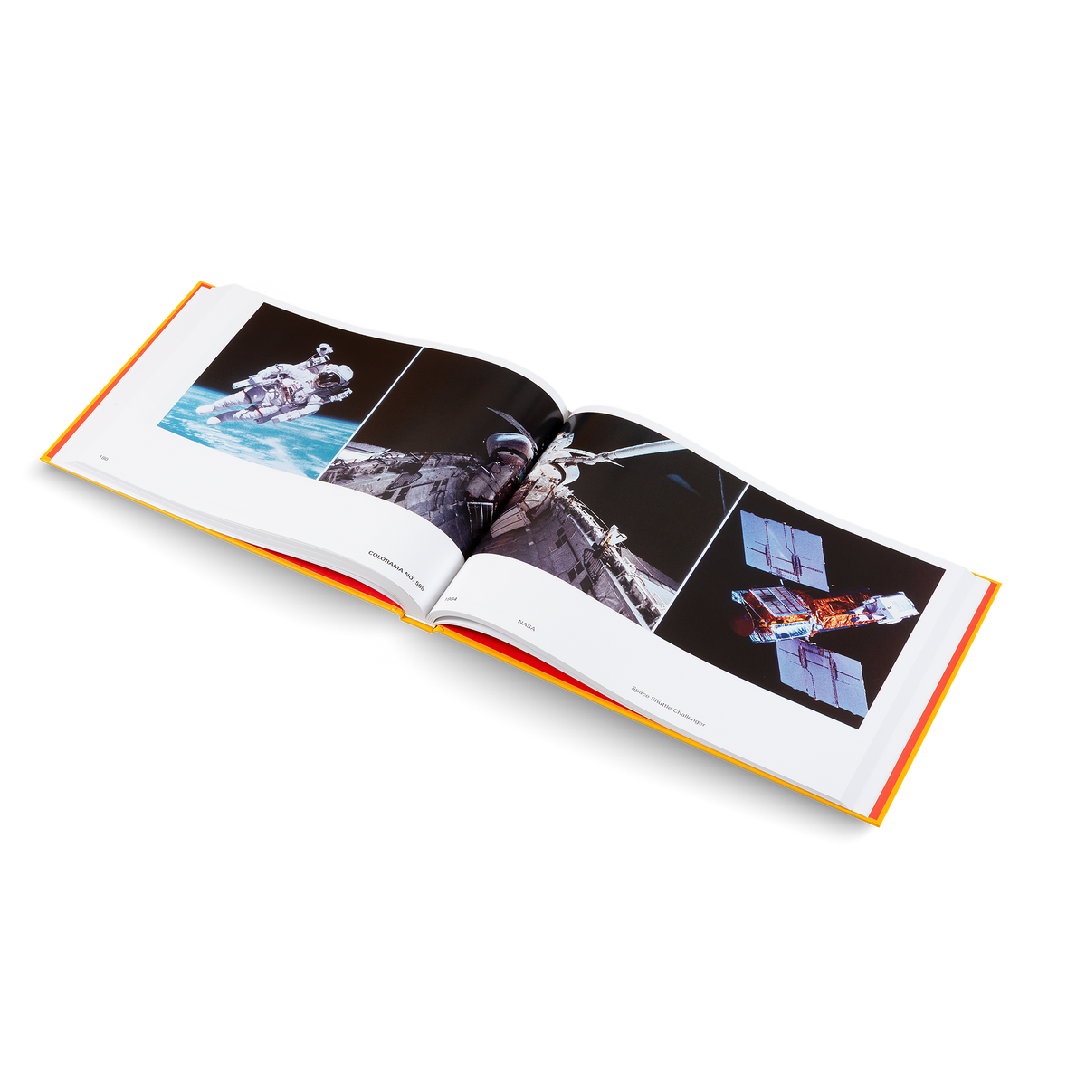 An open hardcover book showing three space-themed photographs on the pages, photographed on a clean white background.