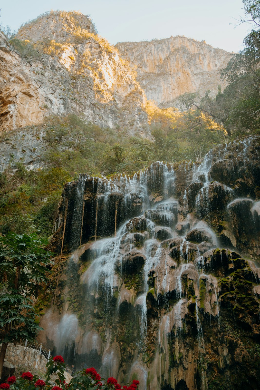 Waterfall cascading down a rocky cliff with mountains in the background