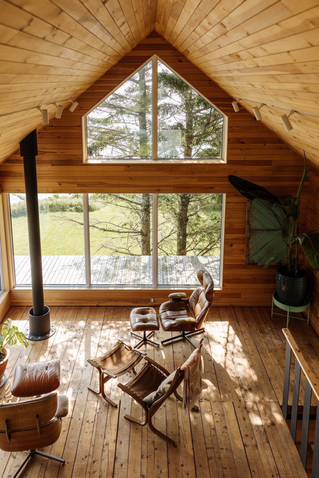 Wooden cabin interior with large windows and wooden furniture.