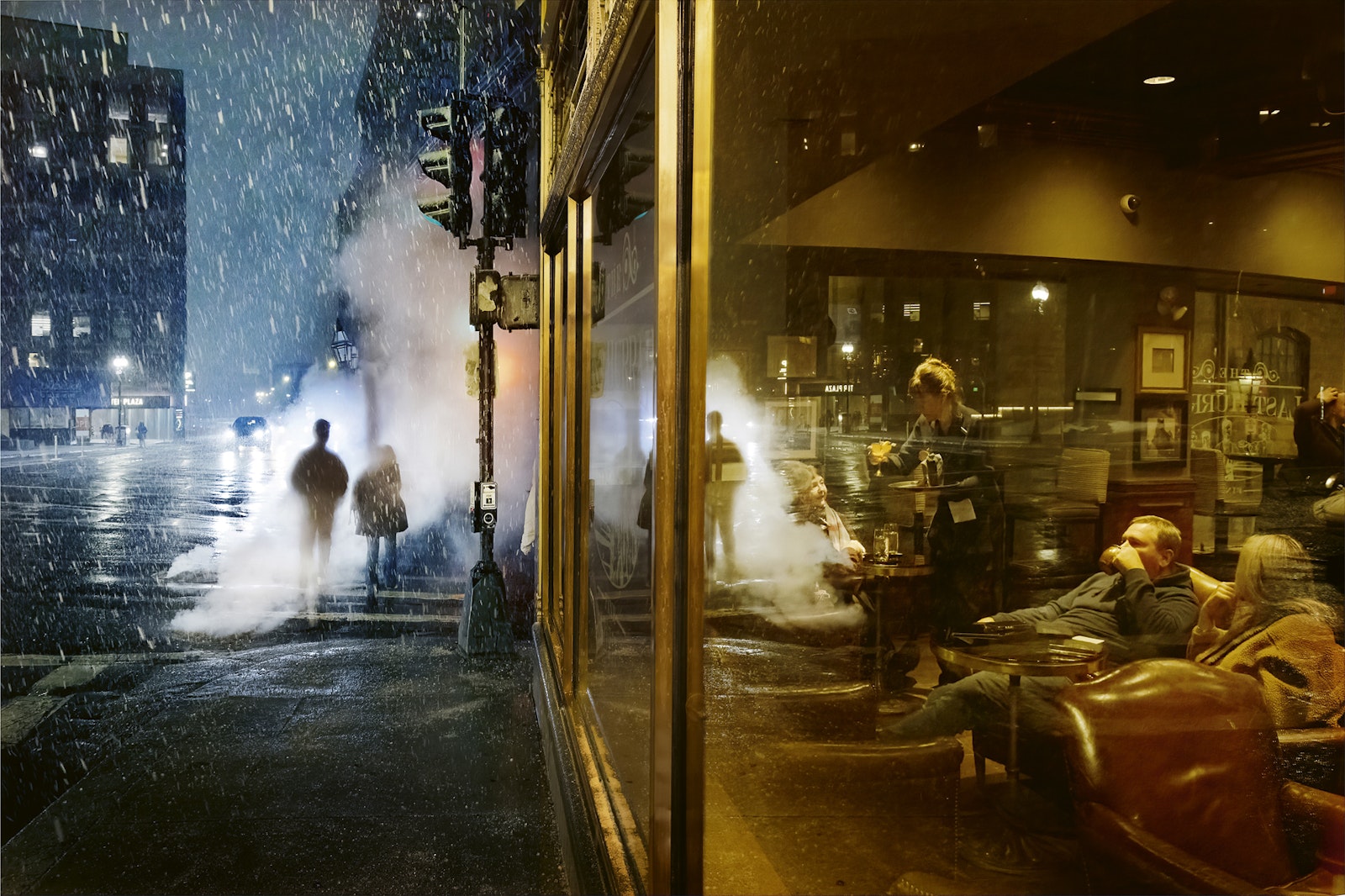 People sitting inside a warmly lit cafe with a snowy street outside