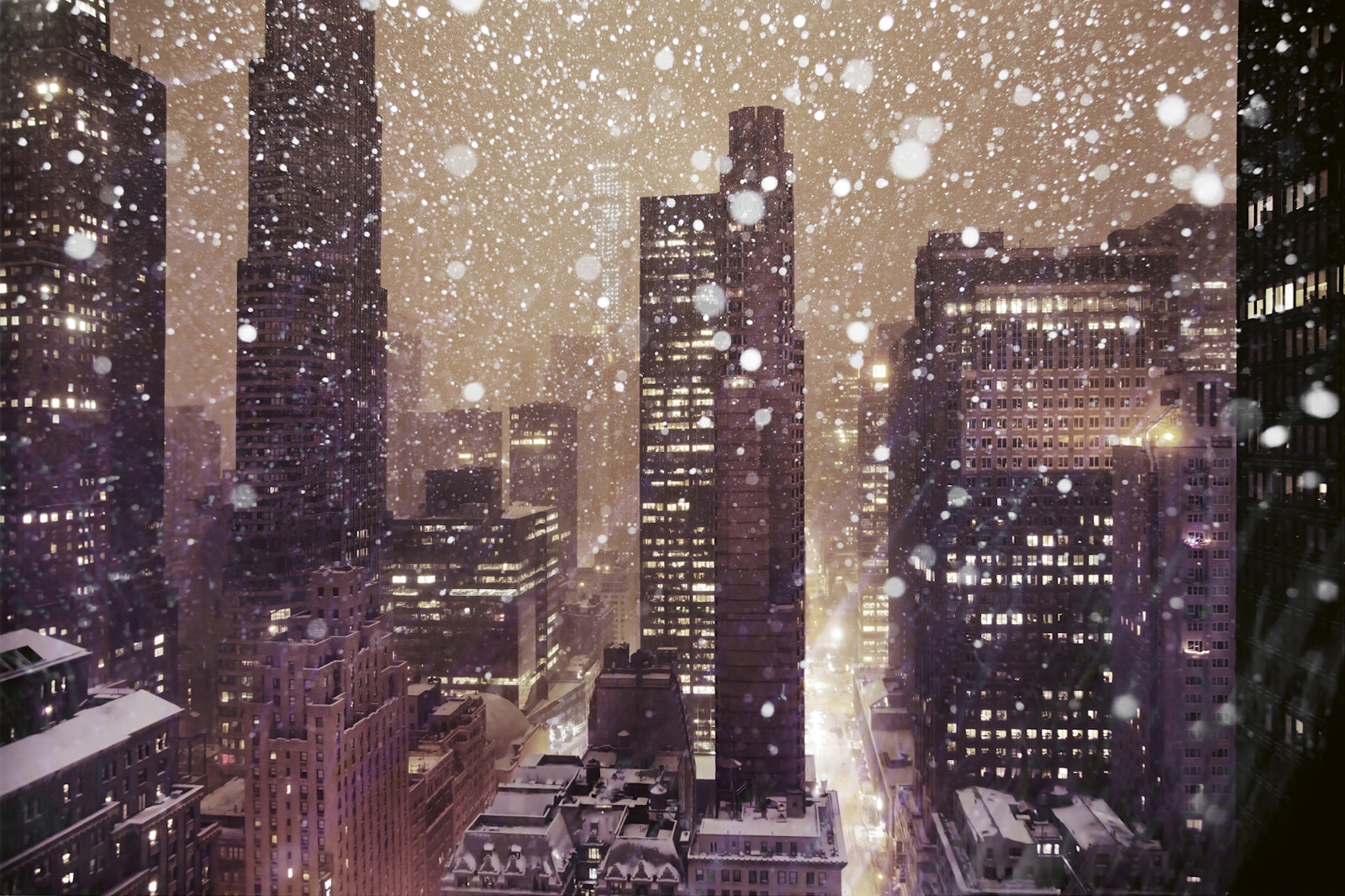 Cityscape at night with snow falling, illuminated skyscrapers