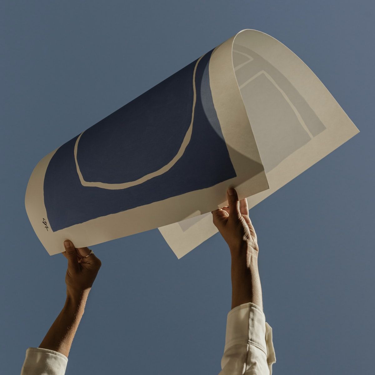 Person holding a large paper cutout of a shoe against a clear blue sky