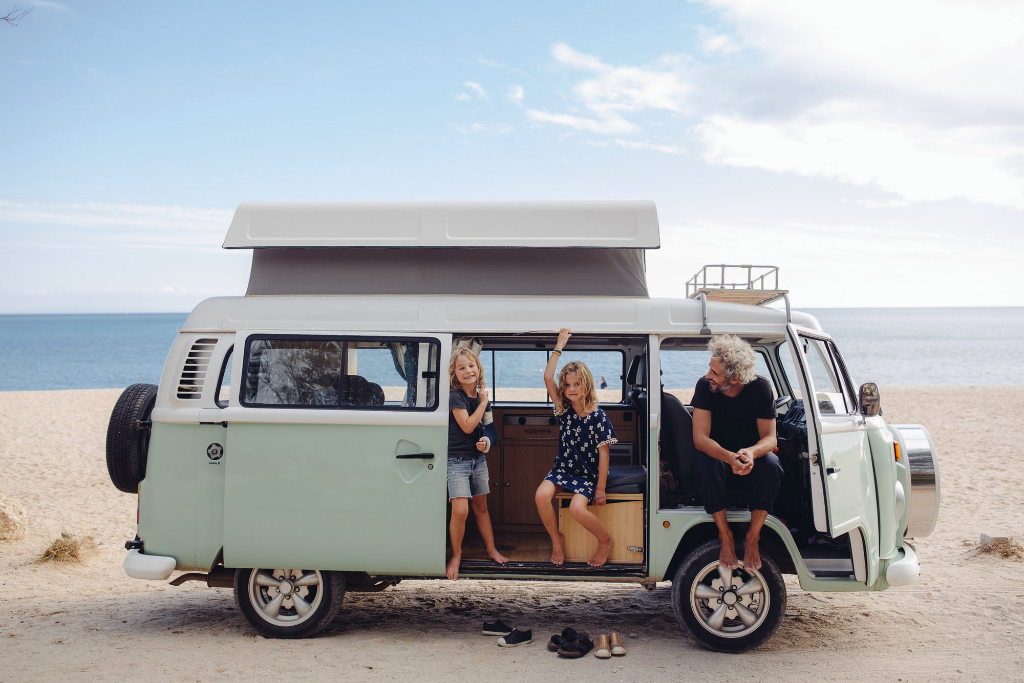 A family in a van on the beach in Family Adventures