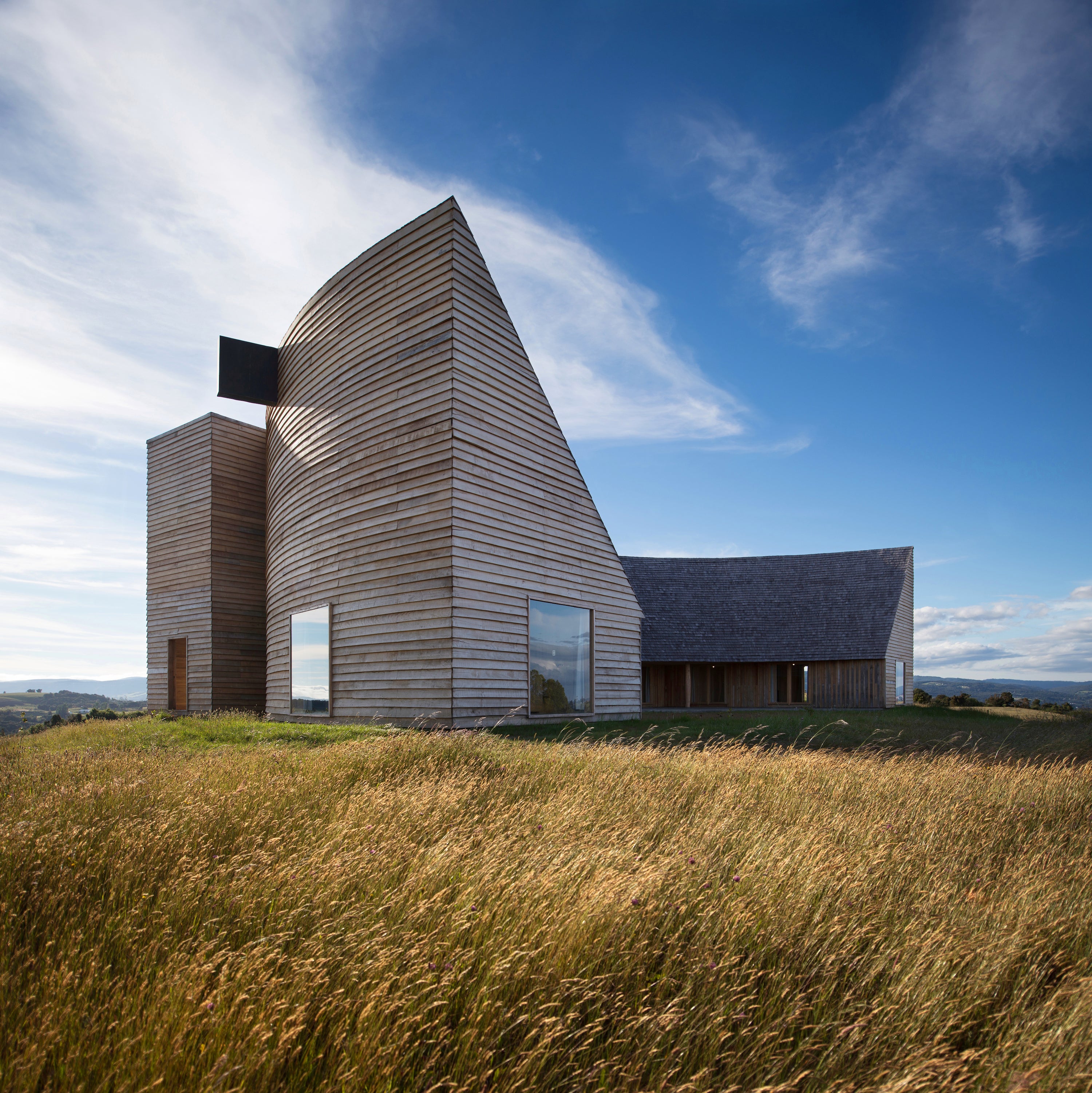 This crescent-shaped home made out of wood and timber is presented in Out of the Woods by gestalten