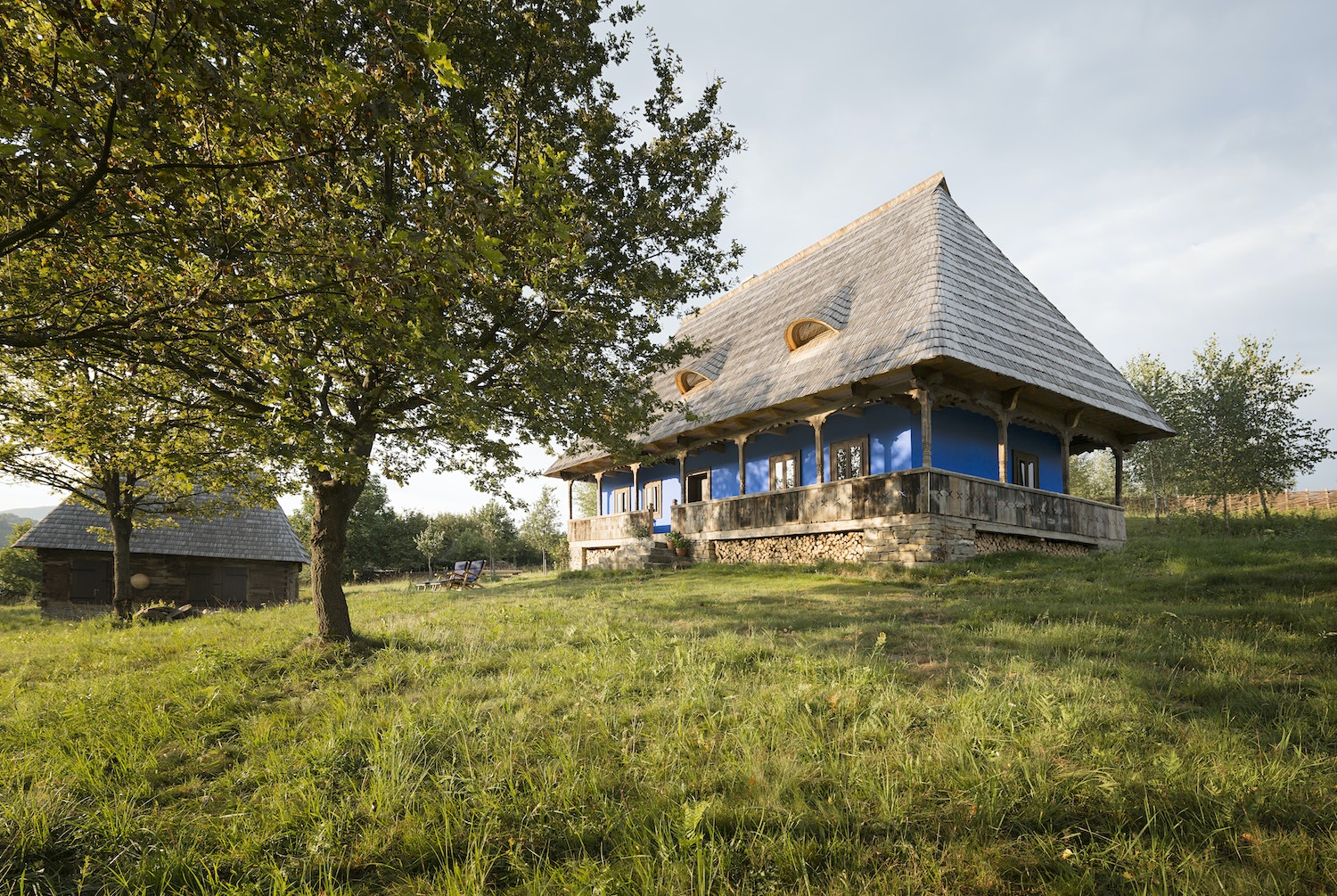 Die Casa Catuna mit Lehmputz und blauem Anstrich steht auf einer Wiese mit Kirsch-, Zwetschgen- und Apfelbäumen – ebenso wie die traditionell eingerichtete Scheune.