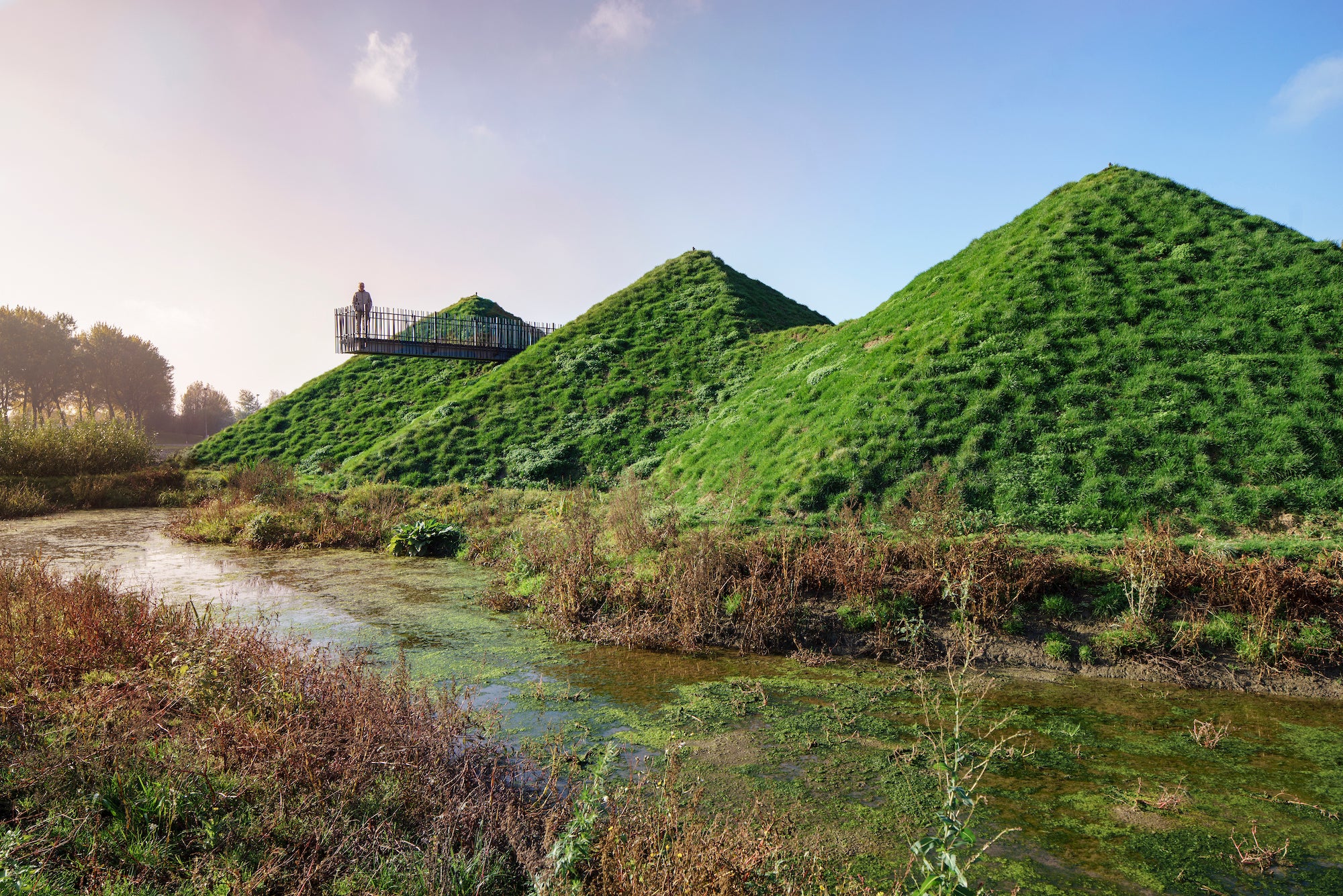 Located on a man-made island in the wetlands of the De Biesbosch National Park, Studio Marco Vermeulen has transformed this local museum: adding a 11,000-square-foot (1,000-square-meter) wing, immersive roofscape, and freshwater tidal park. A green roof blankets the scheme, with a weaving walkway that encourages visitors to explore the terrain. The new wing incorporates generous expanses of floor-to-ceiling, heat-resistant windows, looking out onto the marshland surroundings.